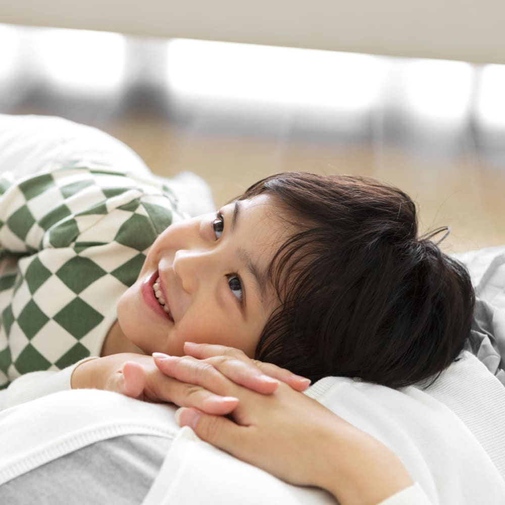 A young boy is across a woman's stomach and smiling.